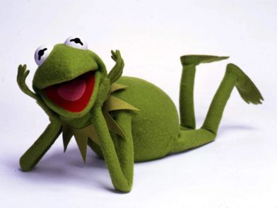 Kermit the Frog rests his head on his hands and smiles.